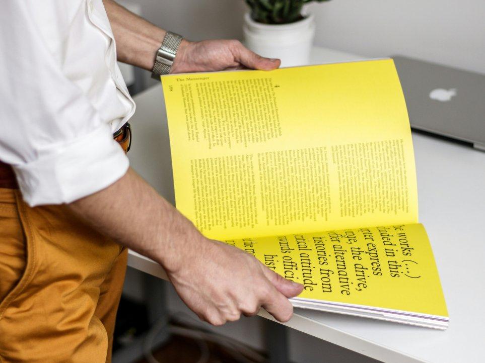 Eine stehende Person, die ein Buch mit gelben Seiten liest