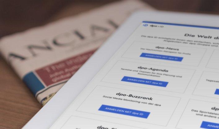 Tablet mit der dpa-ID-App und einer Zeitung auf einem Tisch, der die benutzerfreundliche Plattform von Factorial für den einfachen Zugang zu dpa-Diensten verdeutlicht.