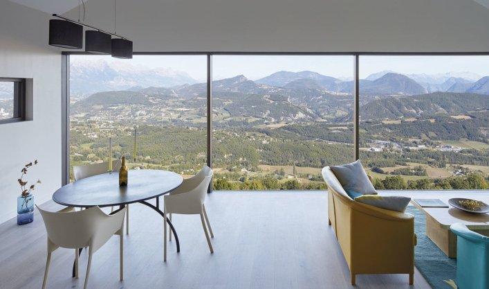 Bild eines Zimmers mit Fensterfront und einer Landschaft im Hintergrund