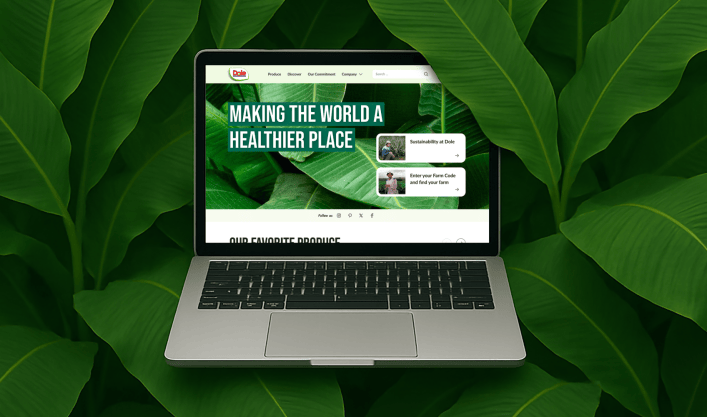 Mockup of a laptop with a view of the Dole website on the screen, surrounded by banana tree leaves.