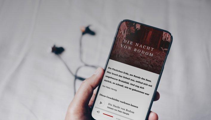 Eine Hand hält ein Smartphone, auf dem ein Artikel inkl. Vorlesefunktion zu sehen ist