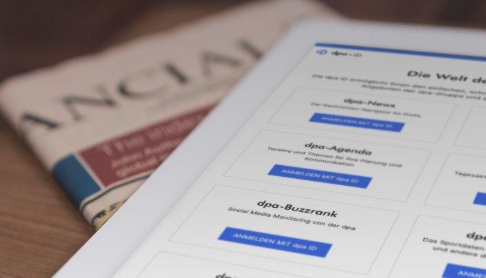 Tablet mit der dpa-ID-App und einer Zeitung auf einem Tisch, der die benutzerfreundliche Plattform von Factorial für den einfachen Zugang zu dpa-Diensten verdeutlicht.