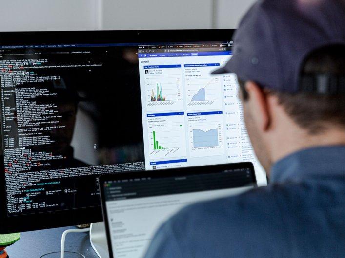 Software developer at their desk. A programme for writing code is open on the screen.