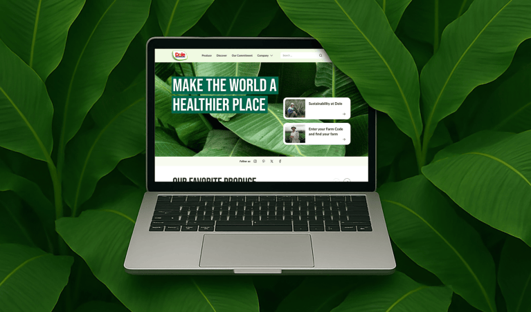 Mockup of a laptop with a view of the Dole website on the screen, surrounded by banana tree leaves.
