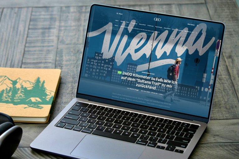 A laptop displaying the GEO website with an article about the city of Vienna on the screen.