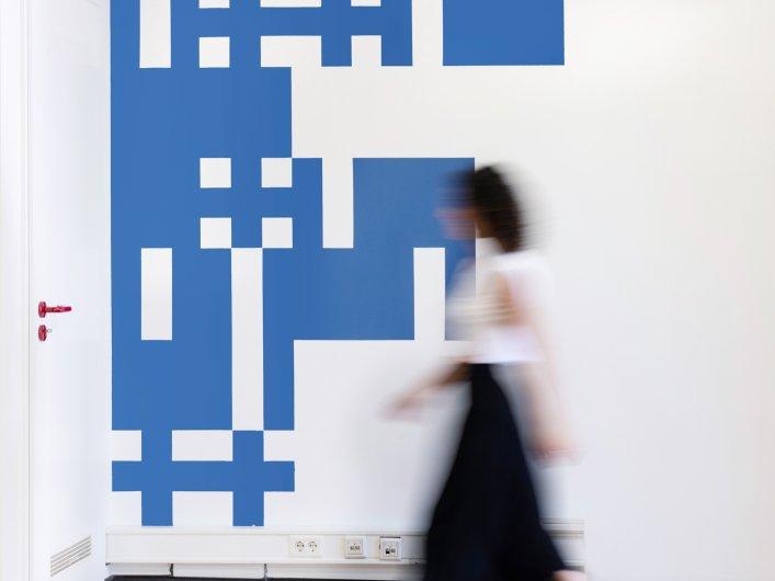 Mitarbeiterin von Factorial läuft am Factorial logo vorrüber.