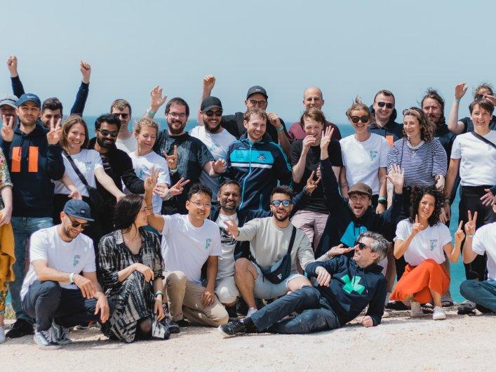 A group of people posing for a photo on the beach, representing the Factorial team.