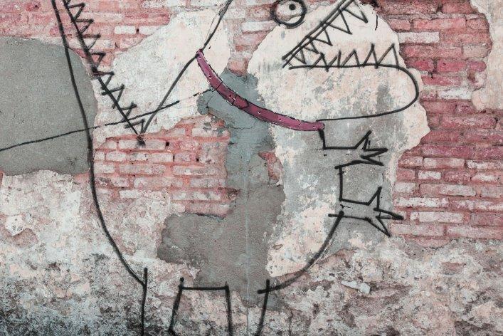 Streetart an Mauer, zu sehen ist ein Kind, dass ein Monster an der Leine hält