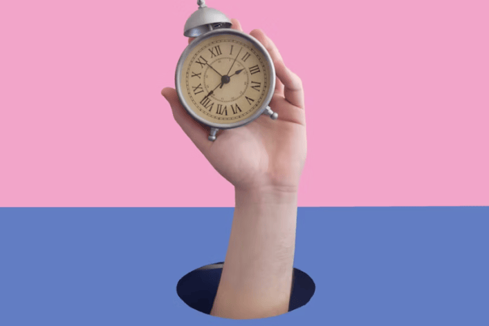 A hand is holding a clock