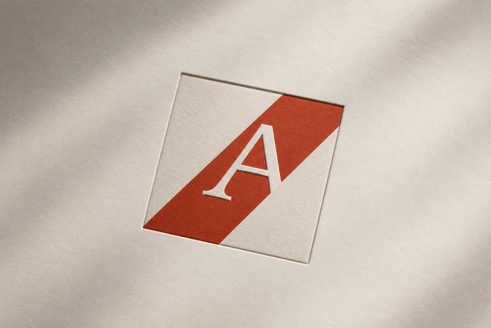 Atelier-Logo von AIncient Labs: weißes Serifen-A auf rotem Diagonalband, geprägt auf Naturpapier