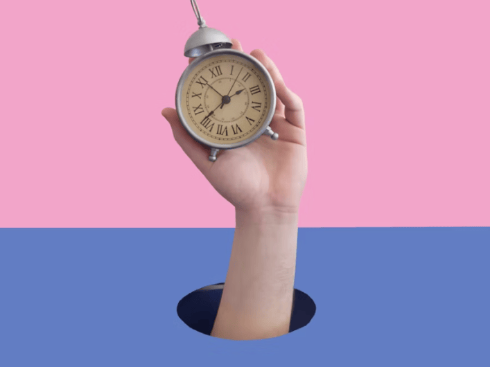 A hand is holding a clock